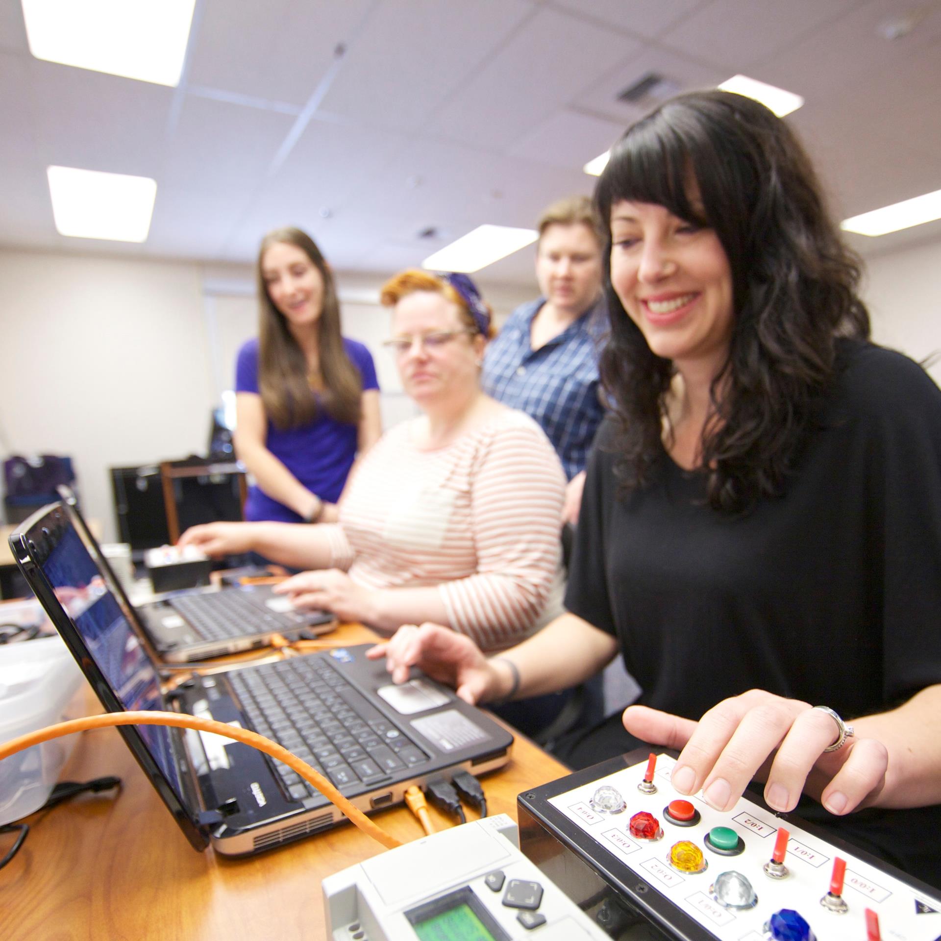 Stock image of women working with electronic switches in computer lab