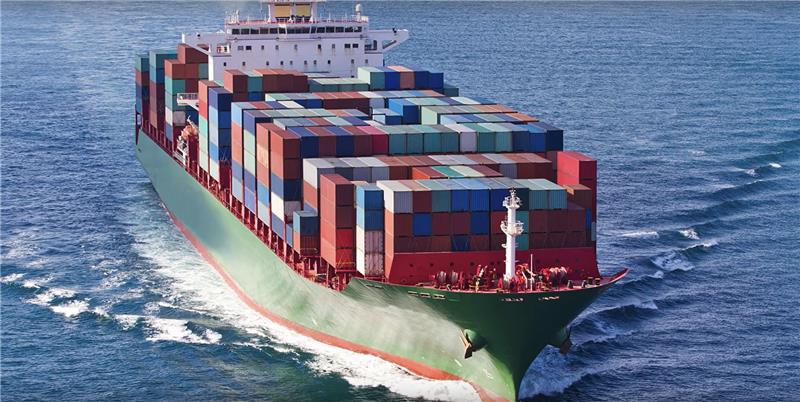 Green boat in the ocean, loaded with multicolored shipping crates